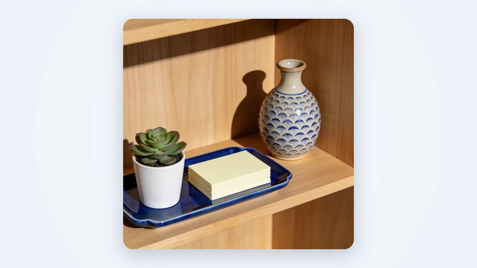 Handmade ceramics, a candle box and a succulent on warm wooden shelves, lit like a small studio shoot