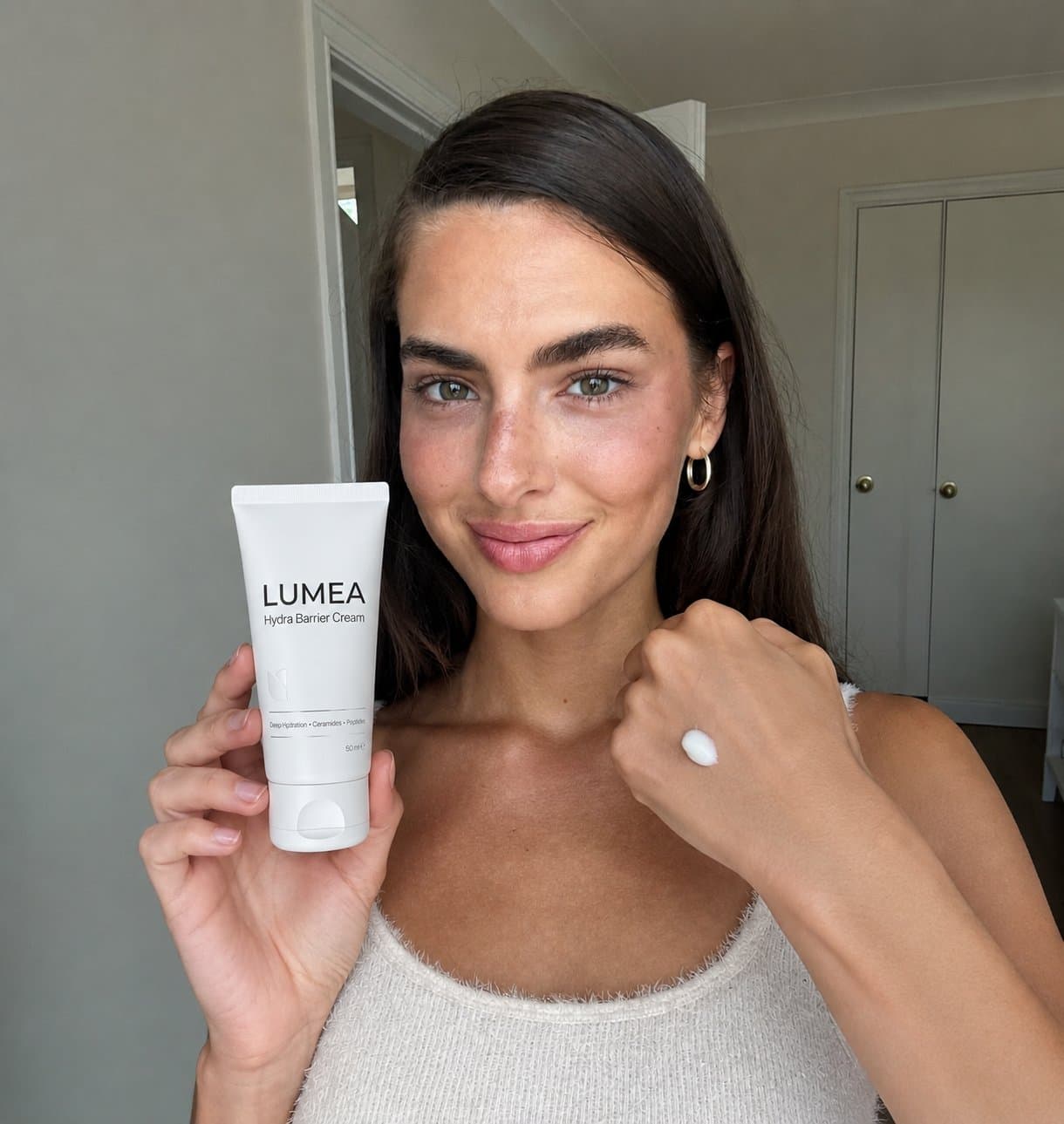 Creator holding a skincare tube to camera, phone-shot UGC style