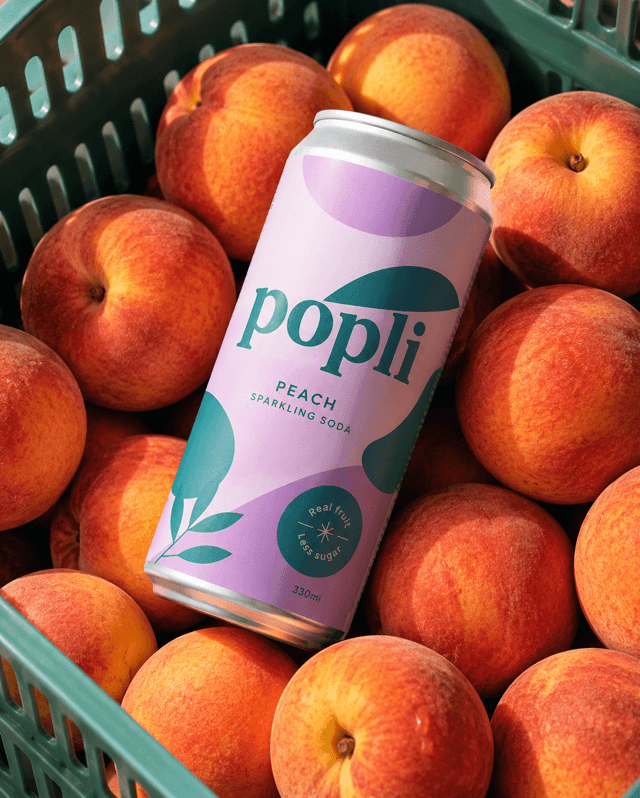 Flatlay of a peach soda can resting on a crate of fresh peaches