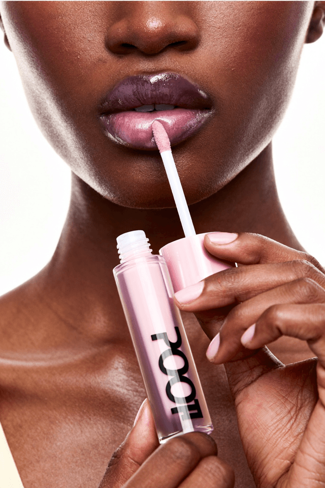 Macro detail of gloss being applied to shimmering lips