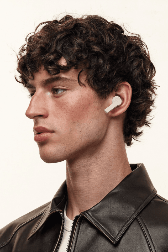 Model in profile wearing a cream wireless earbud